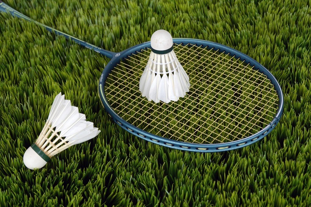A racket and two shuttlecocks resting on grass between games